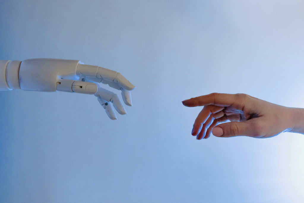 A human hand reaching toward a white robotic hand.